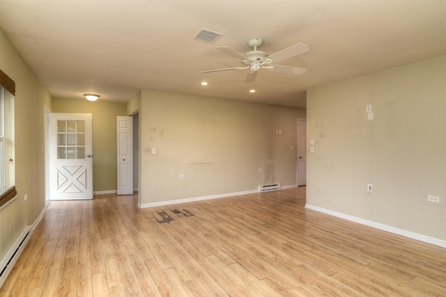 unfurnished room with visible vents, light wood-type flooring, a baseboard heating unit, and baseboards