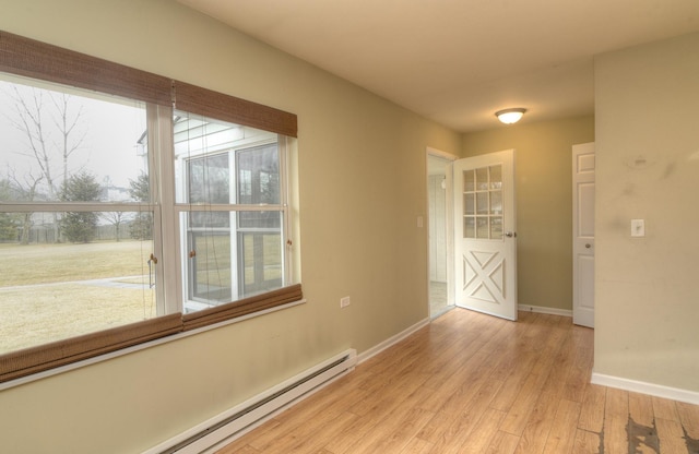 unfurnished room with baseboards, baseboard heating, and light wood-style flooring