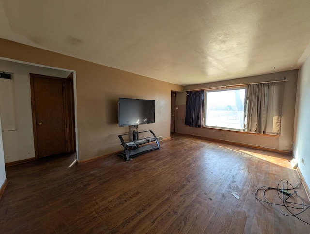 unfurnished living room with wood finished floors and baseboards