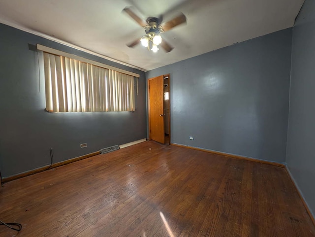 spare room with ceiling fan, visible vents, baseboards, and hardwood / wood-style floors