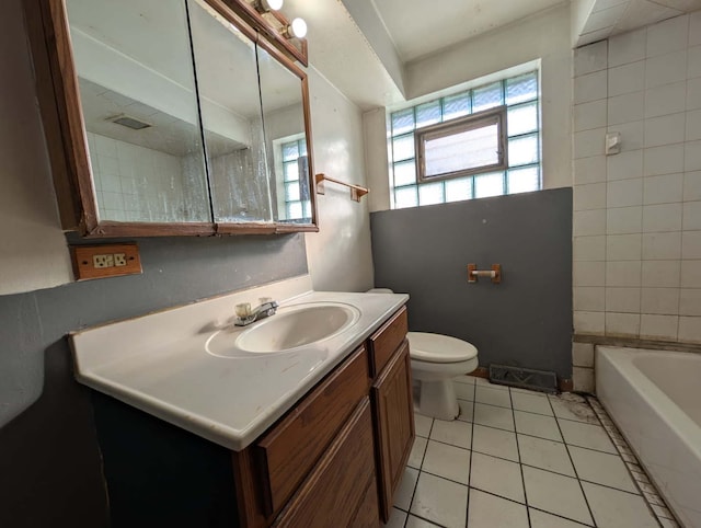 bathroom featuring tile patterned flooring, toilet, a bath, and vanity