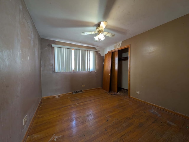 unfurnished bedroom featuring a closet, visible vents, a ceiling fan, and hardwood / wood-style floors