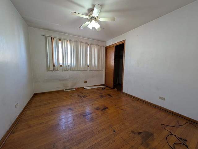 spare room featuring baseboards, visible vents, wood-type flooring, and ceiling fan