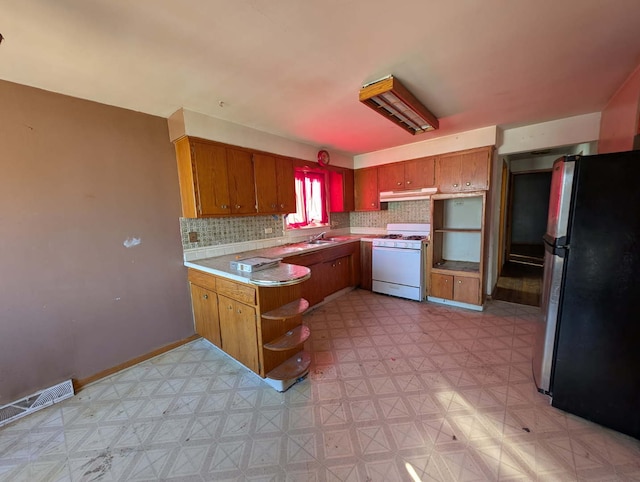 kitchen with under cabinet range hood, gas range gas stove, light floors, and freestanding refrigerator