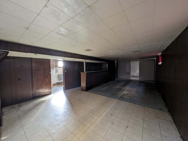 below grade area featuring tile patterned floors and wooden walls