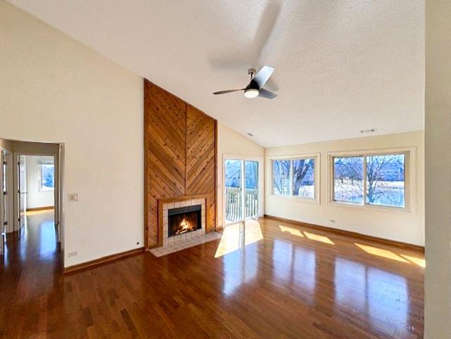 unfurnished living room featuring baseboards, ceiling fan, a tile fireplace, wood finished floors, and a textured ceiling