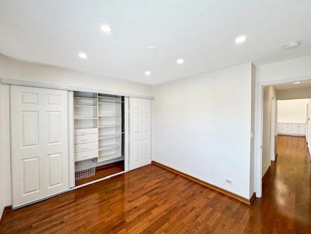 unfurnished bedroom with recessed lighting, wood finished floors, a closet, and baseboards