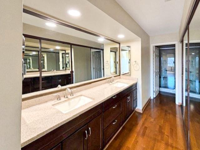 bathroom featuring a sink, recessed lighting, wood finished floors, and double vanity