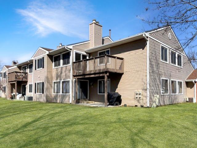 back of property featuring a deck, a chimney, and a yard