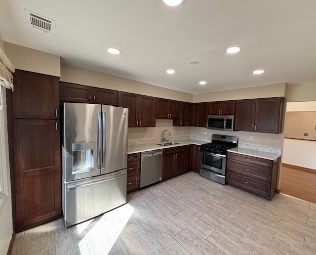 kitchen with visible vents, dark brown cabinets, light countertops, appliances with stainless steel finishes, and a sink