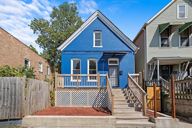 view of front of property featuring a deck, stairway, fence, and brick siding