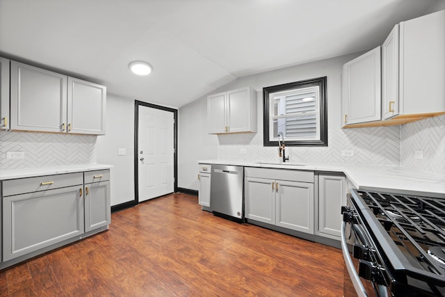 kitchen featuring gray cabinets, a sink, dark wood finished floors, stainless steel appliances, and lofted ceiling