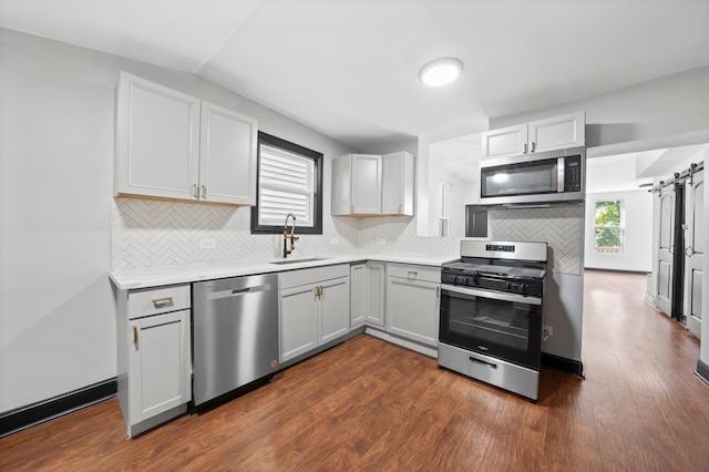 kitchen featuring a wealth of natural light, stainless steel appliances, a barn door, and a sink