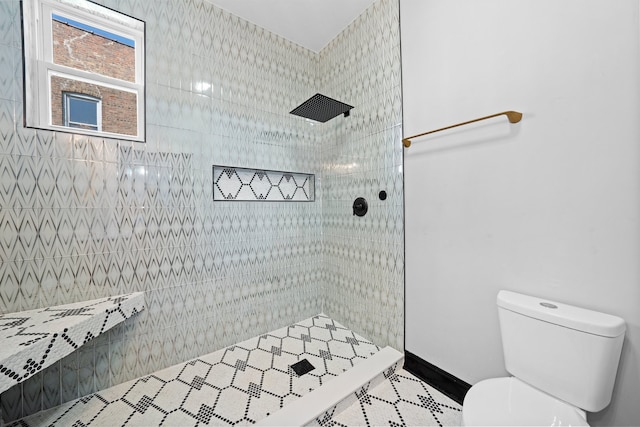 full bathroom with baseboards, toilet, and a tile shower