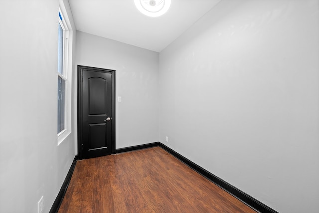 unfurnished room featuring baseboards and dark wood-type flooring