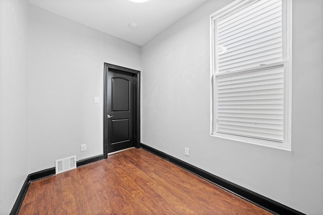 spare room with baseboards, visible vents, and dark wood-style flooring