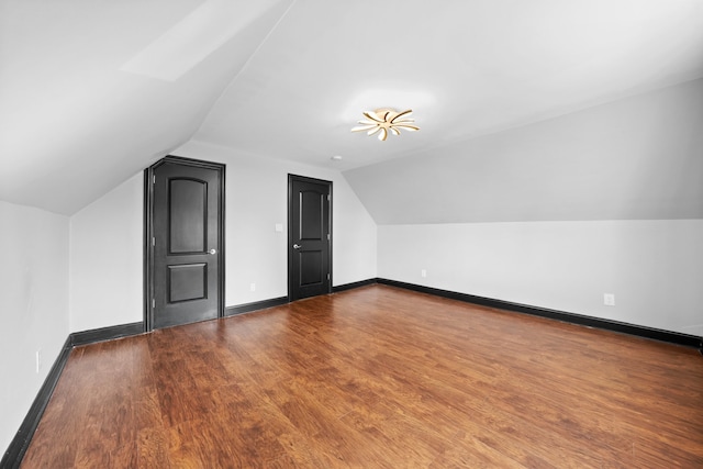 bonus room with baseboards, dark wood finished floors, and vaulted ceiling