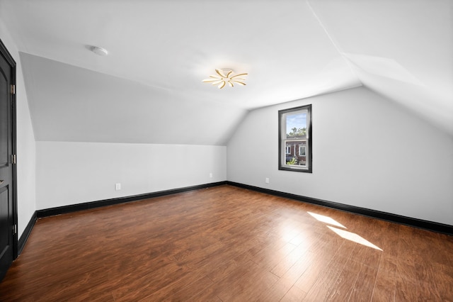 bonus room with baseboards, lofted ceiling, and dark wood finished floors