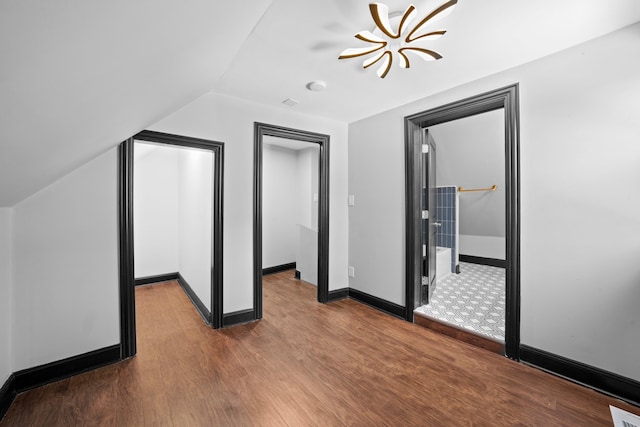 additional living space featuring baseboards, lofted ceiling, visible vents, and wood finished floors