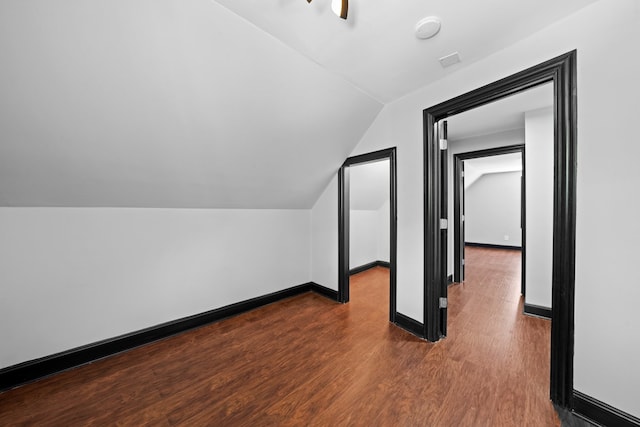 additional living space with dark wood finished floors, vaulted ceiling, and baseboards