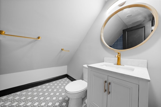 bathroom featuring toilet, vanity, baseboards, and vaulted ceiling