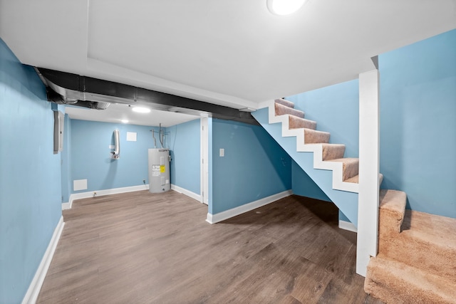 finished below grade area with electric water heater, stairs, baseboards, and wood finished floors