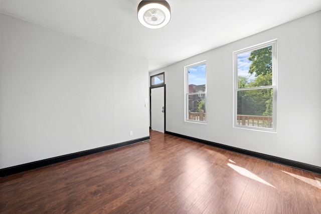 spare room featuring dark wood-type flooring and baseboards