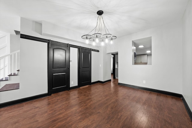 spare room featuring dark wood finished floors, baseboards, stairs, and a barn door