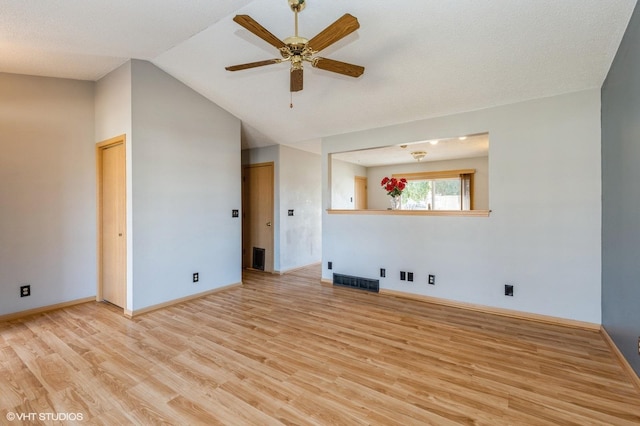 spare room featuring visible vents, baseboards, ceiling fan, lofted ceiling, and light wood-style flooring