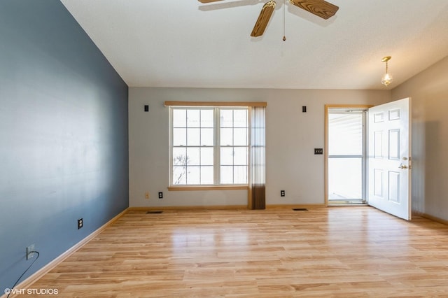 empty room with vaulted ceiling, light wood-style flooring, visible vents, and baseboards