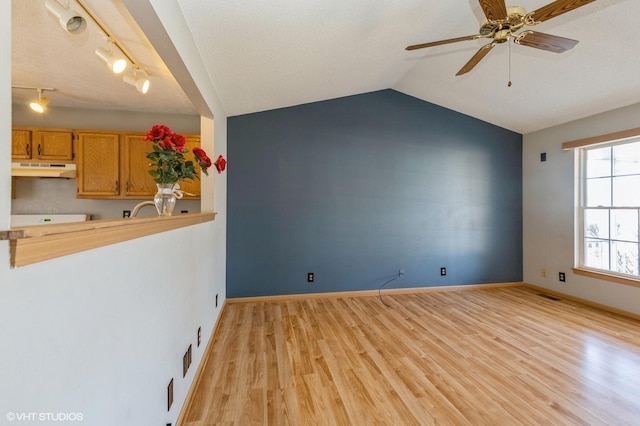 interior space featuring visible vents, baseboards, light wood finished floors, lofted ceiling, and ceiling fan