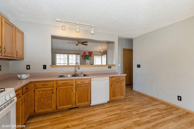 kitchen with white appliances, a sink, light countertops, light wood-style floors, and a textured ceiling