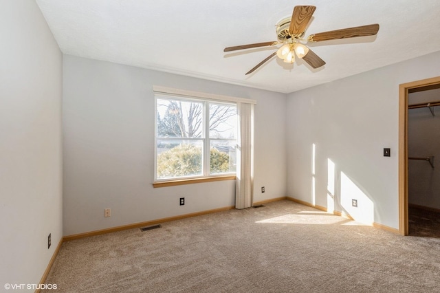 carpeted spare room featuring a ceiling fan, baseboards, and visible vents