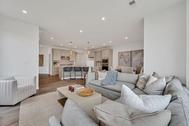 living room featuring light wood-type flooring, visible vents, and recessed lighting