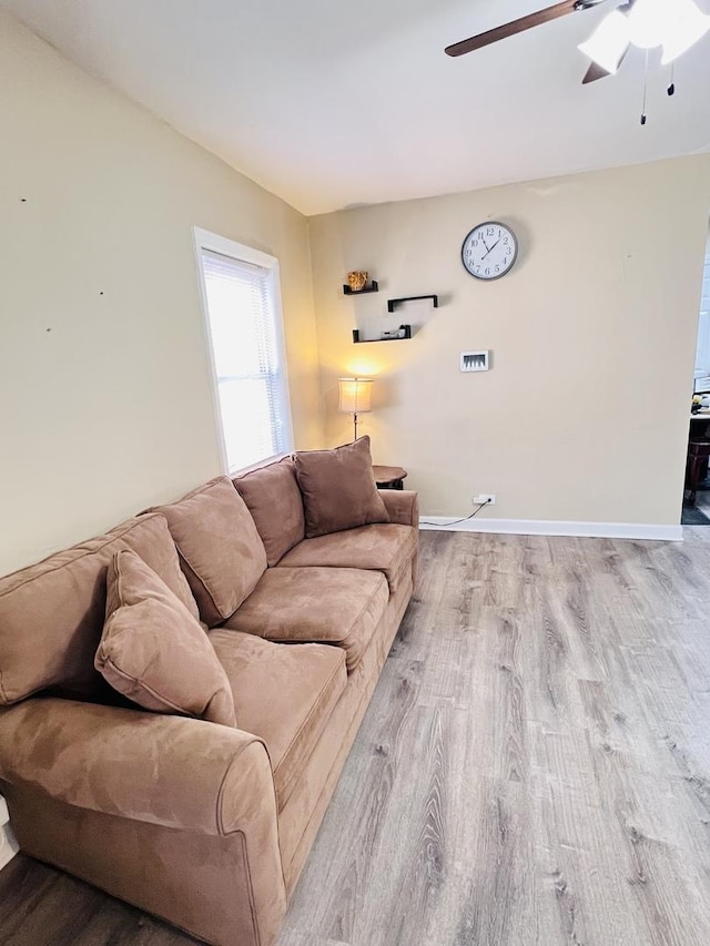 living room featuring baseboards, wood finished floors, and ceiling fan