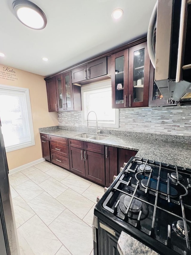 kitchen featuring tasteful backsplash, gas range, a healthy amount of sunlight, and a sink