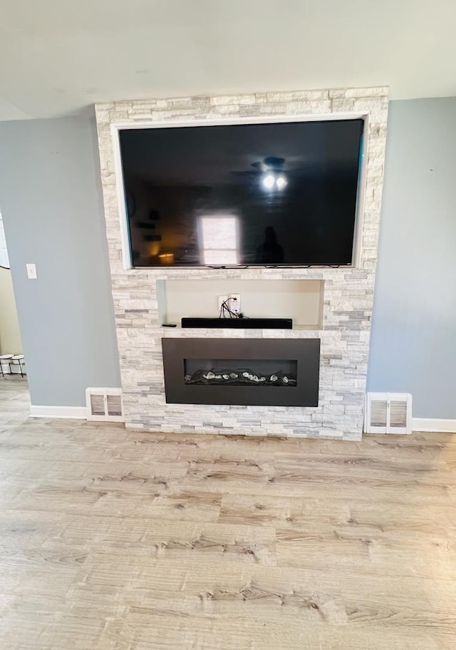 interior details with visible vents, a fireplace, baseboards, and wood finished floors