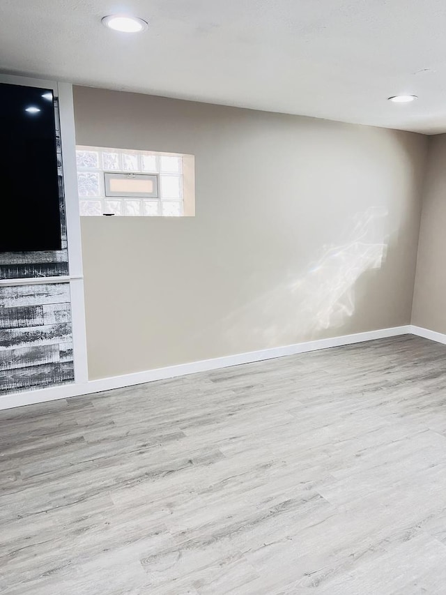 unfurnished room featuring recessed lighting, a fireplace, baseboards, and wood finished floors