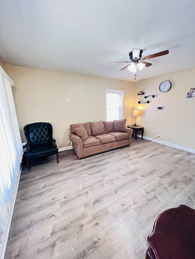 living area with baseboards, wood finished floors, and ceiling fan