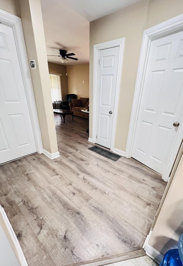 interior space with baseboards, a ceiling fan, and wood finished floors