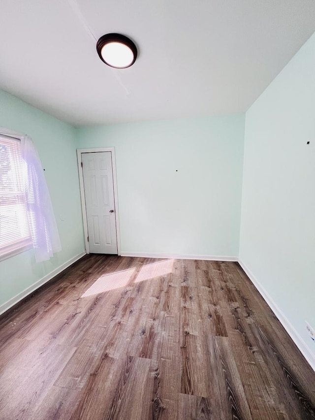 spare room featuring baseboards and wood finished floors