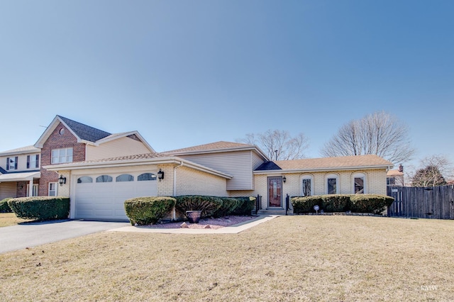 view of front of home with brick siding, a front lawn, fence, and a garage