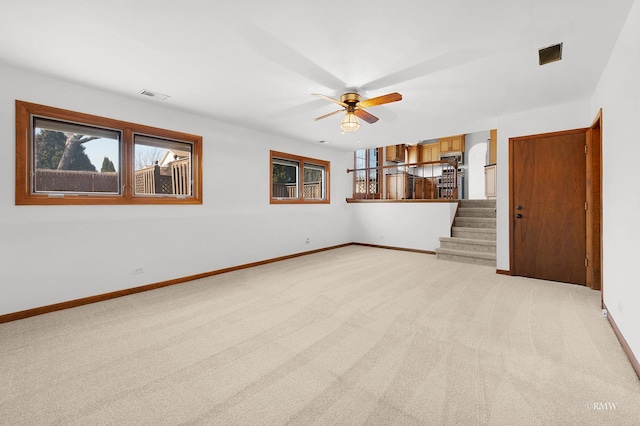 unfurnished living room with visible vents, light carpet, baseboards, and stairs