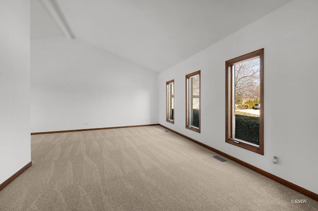 empty room featuring lofted ceiling, baseboards, visible vents, and light carpet