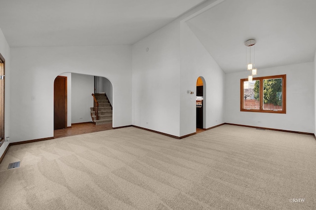 unfurnished room with arched walkways, carpet flooring, and visible vents