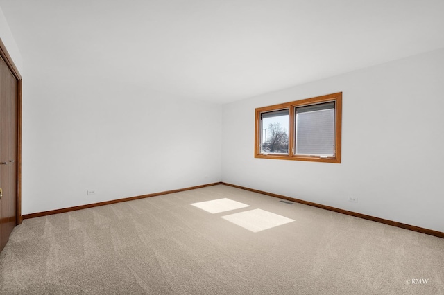 carpeted spare room featuring visible vents and baseboards