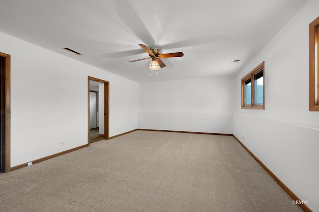 spare room with light carpet, visible vents, ceiling fan, and baseboards