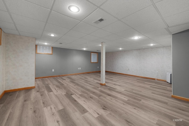 finished basement with wood finished floors, visible vents, a drop ceiling, and baseboards