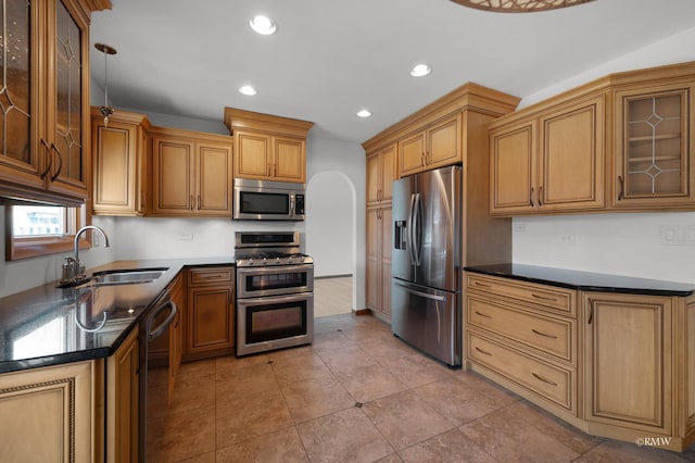 kitchen featuring recessed lighting, a sink, glass insert cabinets, appliances with stainless steel finishes, and dark countertops