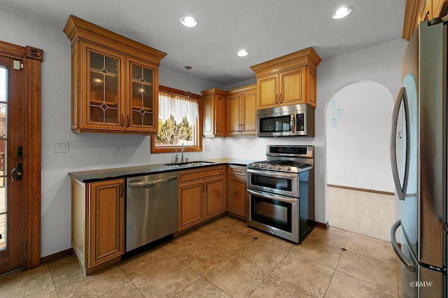 kitchen featuring brown cabinetry, recessed lighting, stainless steel appliances, and a sink